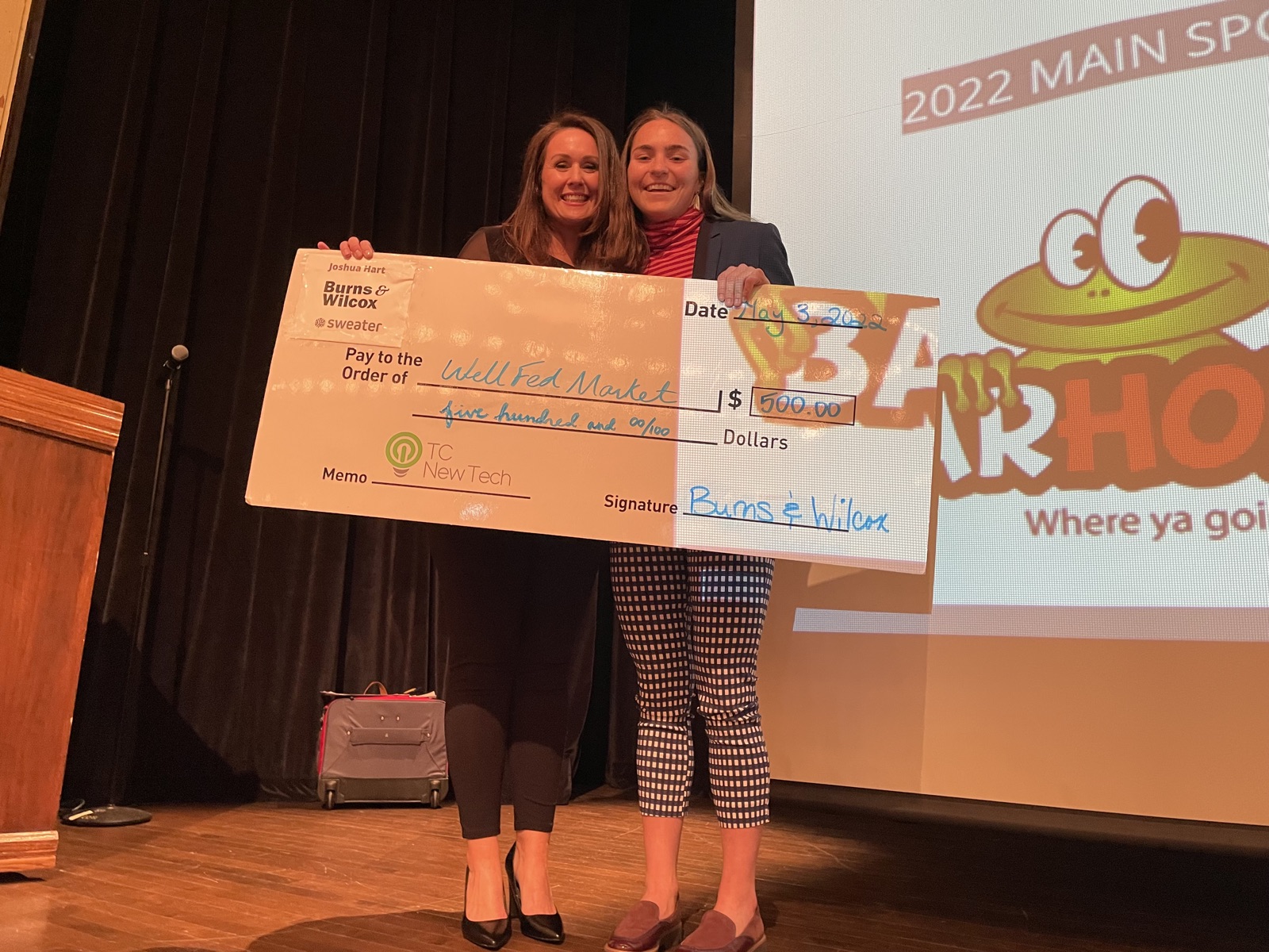 Elizabeth Saunders accepting the Wellfed Market funding check alongside a TCNewTech representative